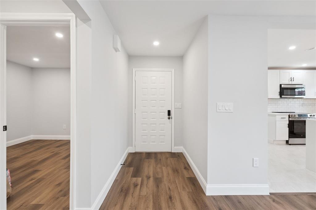 An entryway with wood-look flooring leads to a white front door and an adjacent kitchen — 530 HUNTER CIRCLE, KISSIMMEE, FL