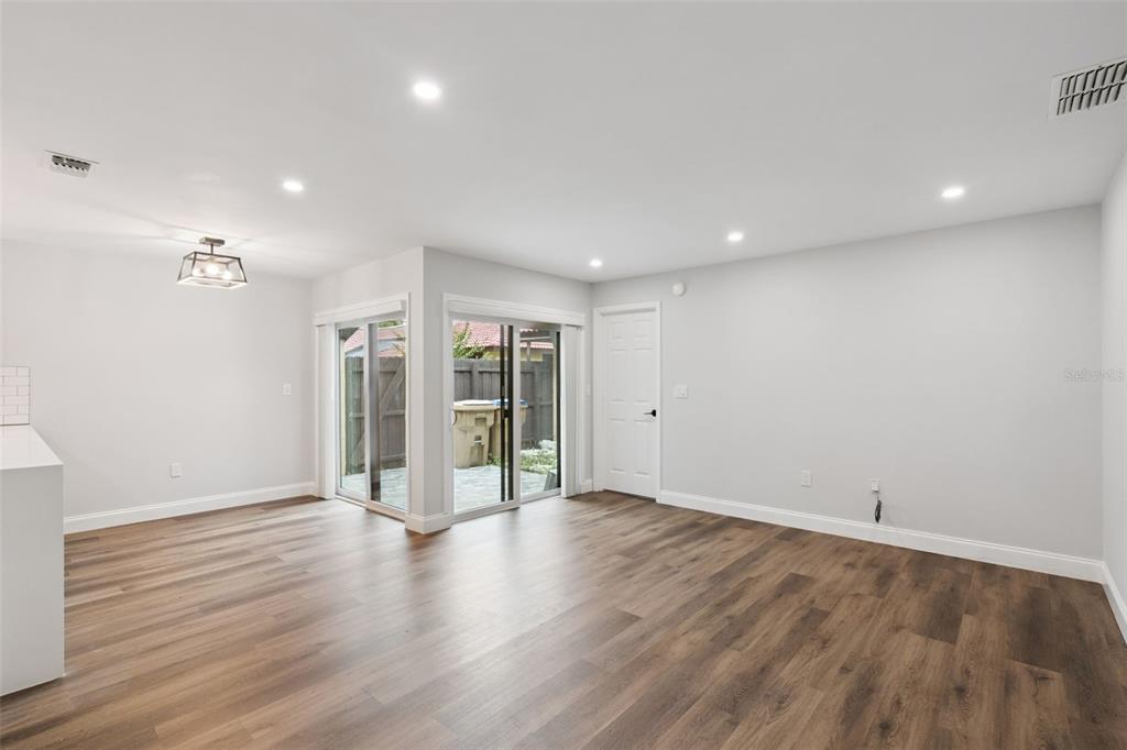 An empty room with wood-look flooring, recessed lighting, a dining pendant, and sliding glass doors — 530 HUNTER CIRCLE, KISSIMMEE, FL