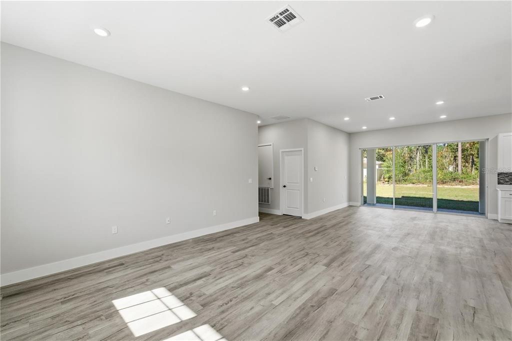 An open-concept living area features light gray walls, wood-look flooring, recessed lighting, and sliding doors — 13205 SW 65TH CIRCLE, OCALA, FL