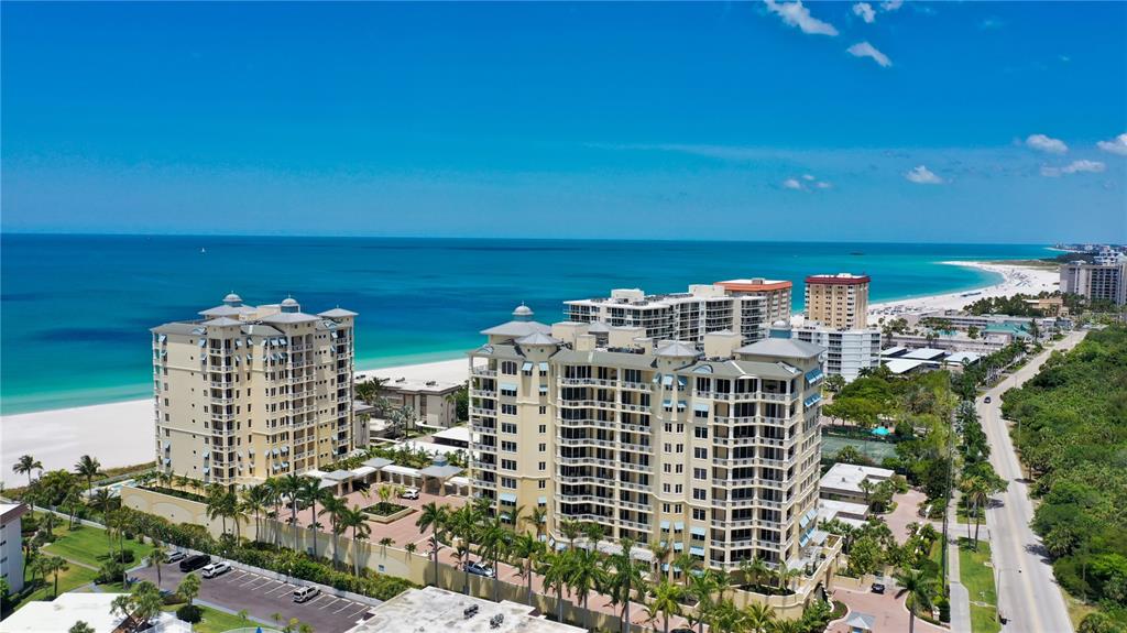 An aerial view shows two large, multi-story residential buildings situated along a sandy beach — 2050 BENJAMIN FRANKLIN DRIVE UNIT B704, SARASOTA, FL
