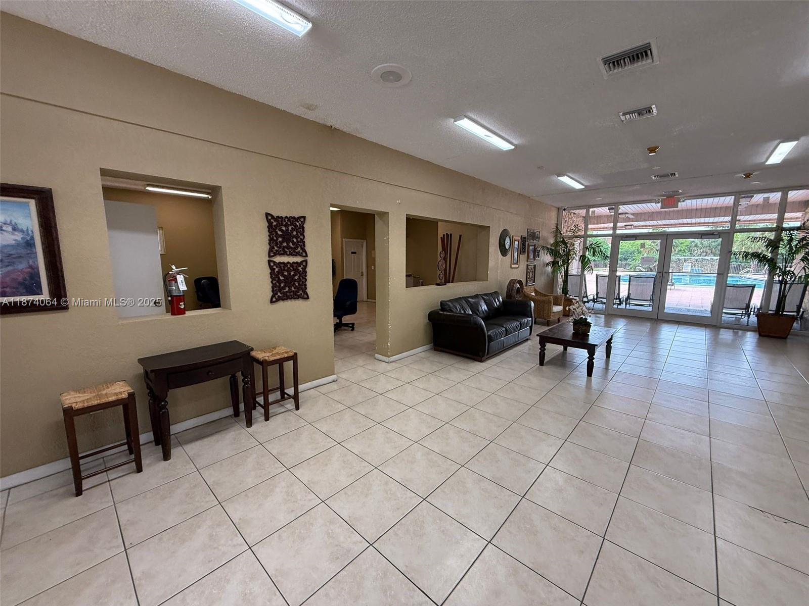 A spacious lobby features tile flooring, a seating area, and large windows overlooking a pool — 6940 Miami Gardens Dr # 122, Hialeah FL 33015, HIALEAH, FL