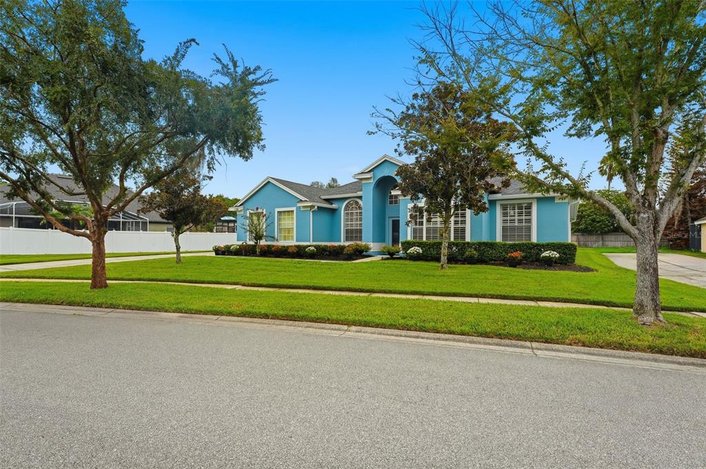 A blue single-story house with a front lawn, trees, and a white fence — 731 DIVINE CIRCLE, ORLANDO, FL