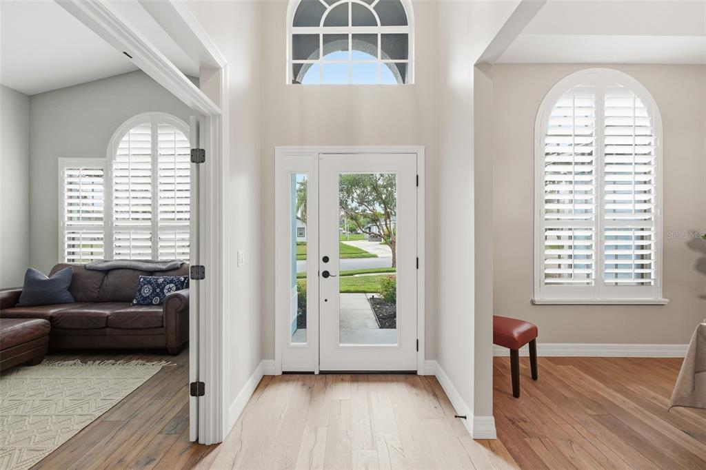 A bright entryway features a white front door, arched windows with shutters, and hardwood flooring — 731 DIVINE CIRCLE, ORLANDO, FL