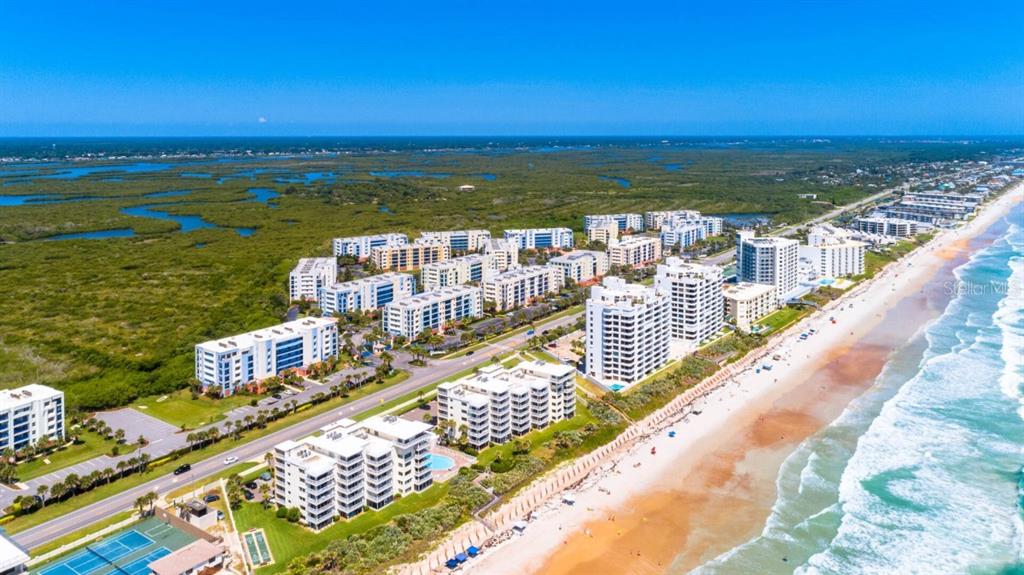 An aerial view of beachfront condominium buildings along a coastline with a large marshland area — 5300 S ATLANTIC AVENUE UNIT 4-302, NEW SMYRNA BEACH, FL