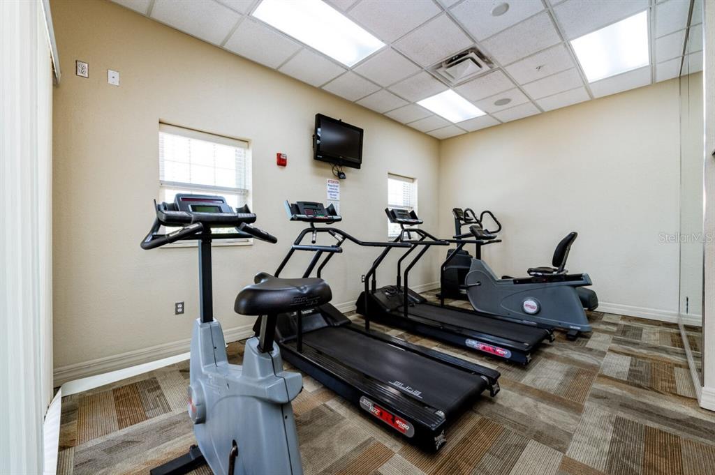 A small fitness room features two treadmills, two stationary bikes, and a wall-mounted television — 5300 S ATLANTIC AVENUE UNIT 4-302, NEW SMYRNA BEACH, FL