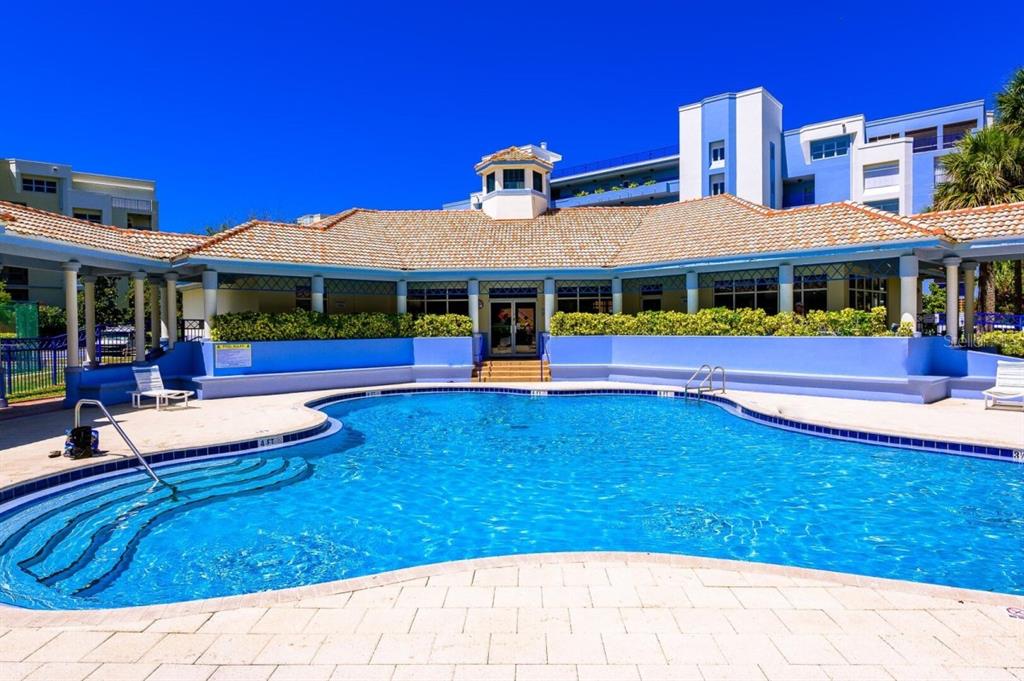 A swimming pool with a tiled deck sits in front of a building with a roof — 5300 S ATLANTIC AVENUE UNIT 4-302, NEW SMYRNA BEACH, FL