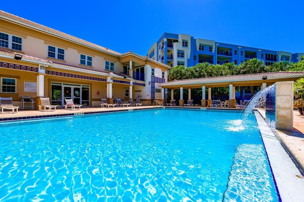 A swimming pool with a water feature sits in front of a multi-story residential building — 5300 S ATLANTIC AVENUE UNIT 4-302, NEW SMYRNA BEACH, FL