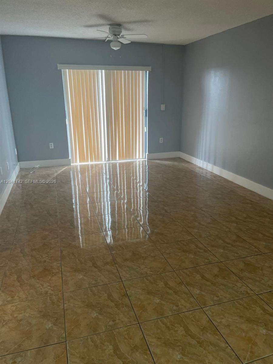 An empty room features light gray walls, a ceiling fan, and glossy tan tiled flooring — 6950 W 6th Ave # 308, Hialeah FL 33014, HIALEAH, FL