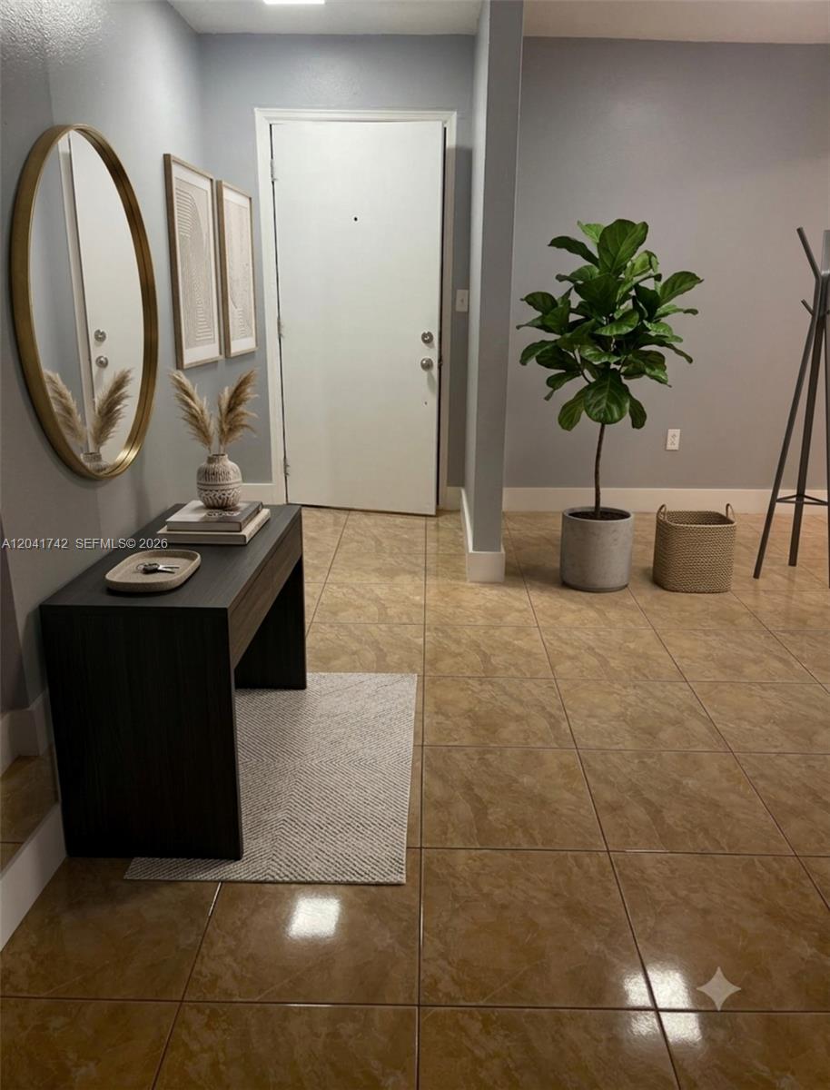 An entryway features a dark wood console table, a round gold mirror, and a potted plant — 6950 W 6th Ave # 308, Hialeah FL 33014, HIALEAH, FL