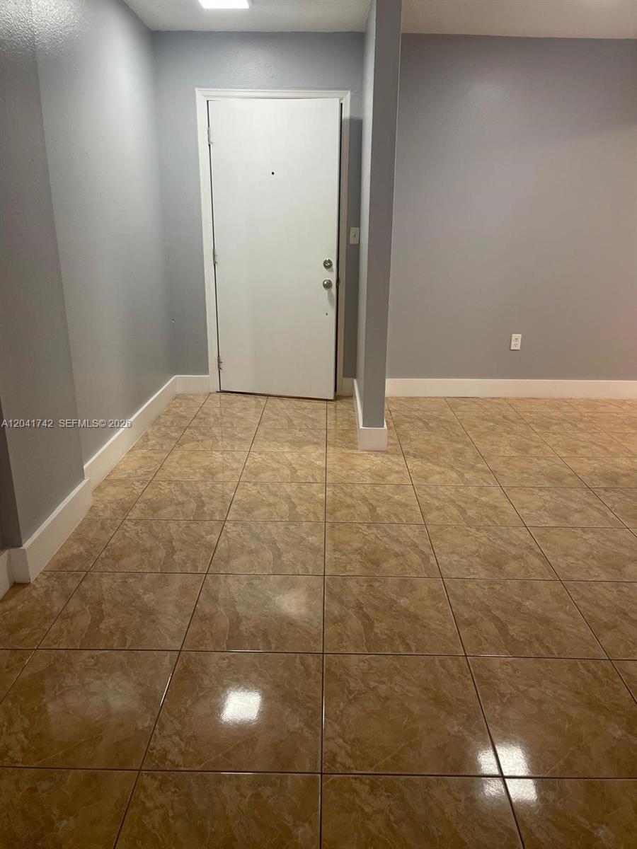 An interior view shows a room with light gray walls, white trim, and tan tile flooring — 6950 W 6th Ave # 308, Hialeah FL 33014, HIALEAH, FL