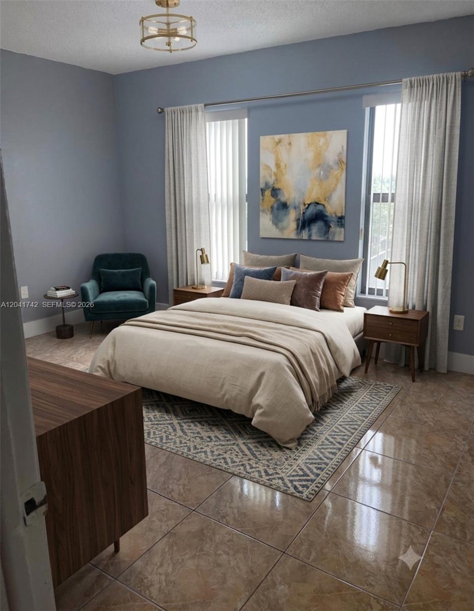 A bedroom features a bed with neutral bedding, a blue armchair, and tile flooring — 6950 W 6th Ave # 308, Hialeah FL 33014, HIALEAH, FL