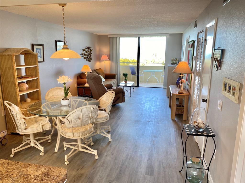 A living and dining area features a glass table, wicker shelving, and a balcony view — 5915 SEA RANCH DRIVE UNIT 509W, HUDSON, FL