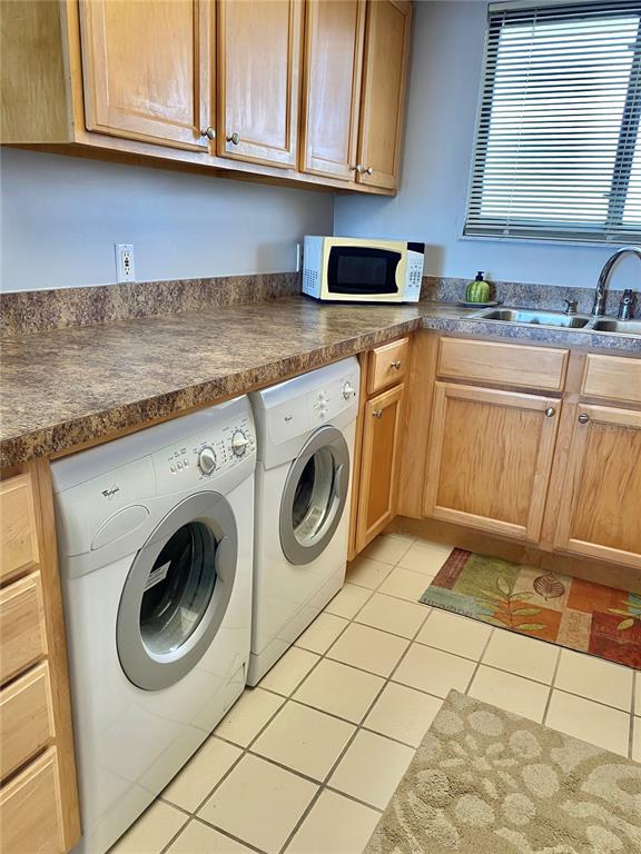 A laundry room features light wood cabinets, a dark countertop, and two white front-loading machines — 5915 SEA RANCH DRIVE UNIT 509W, HUDSON, FL
