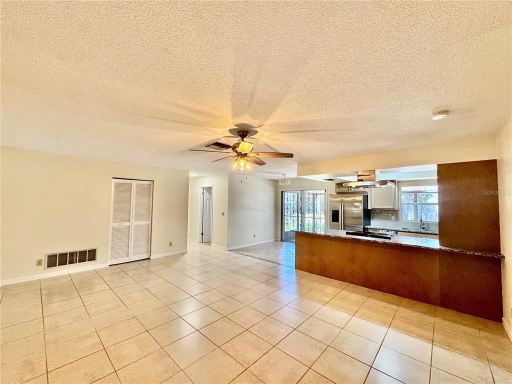 An open-concept living area features light tile flooring, a ceiling fan, and a kitchen peninsula — 29 FOXHALL LANE, PALM COAST, FL