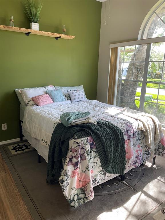 A bedroom features a green accent wall, a floral bedspread, and a large arched window — 1826 EAGLE RIDGE BOULEVARD, PALM HARBOR, FL
