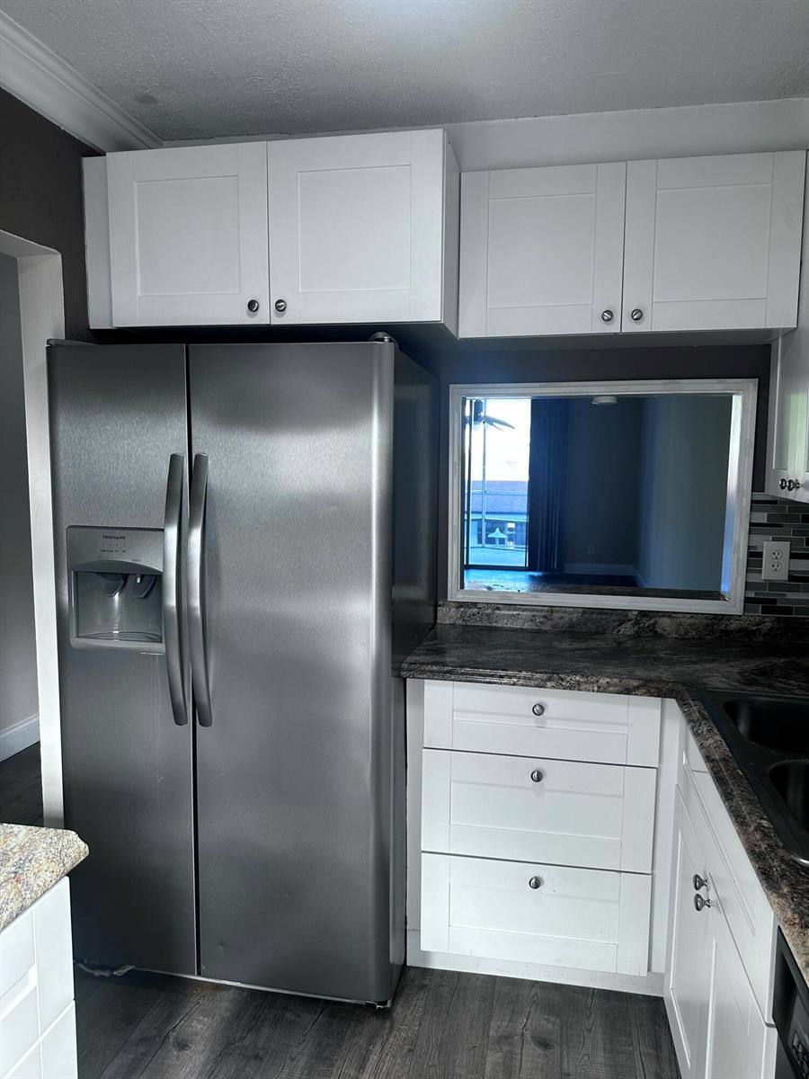 A kitchen features a stainless steel refrigerator, white cabinets, and a pass-through window — 1040 SE 4th Avenue # 222, Deerfield Beach FL 33441, DEERFIELD BEACH, FL