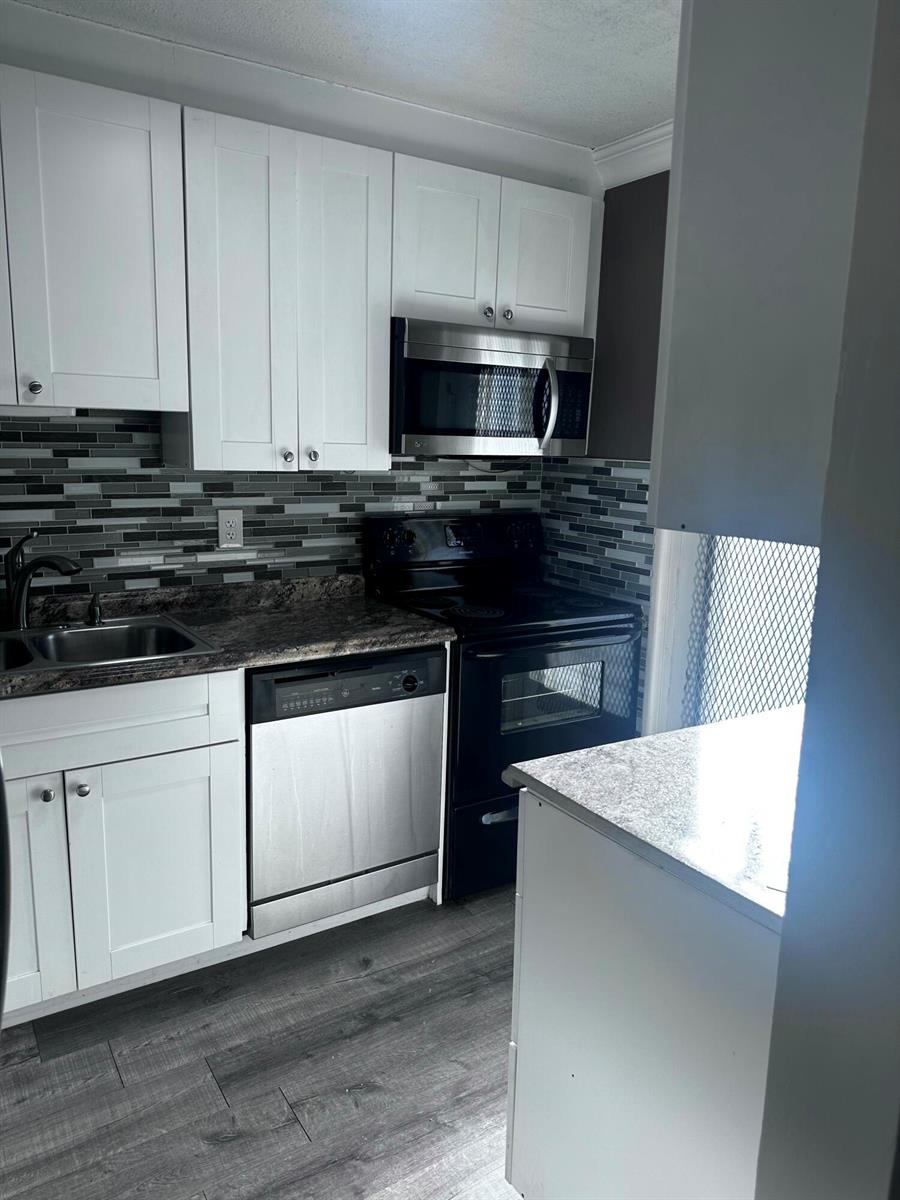 A kitchen with white cabinets, stainless steel appliances, a dark countertop, and a tiled backsplash — 1040 SE 4th Avenue # 222, Deerfield Beach FL 33441, DEERFIELD BEACH, FL