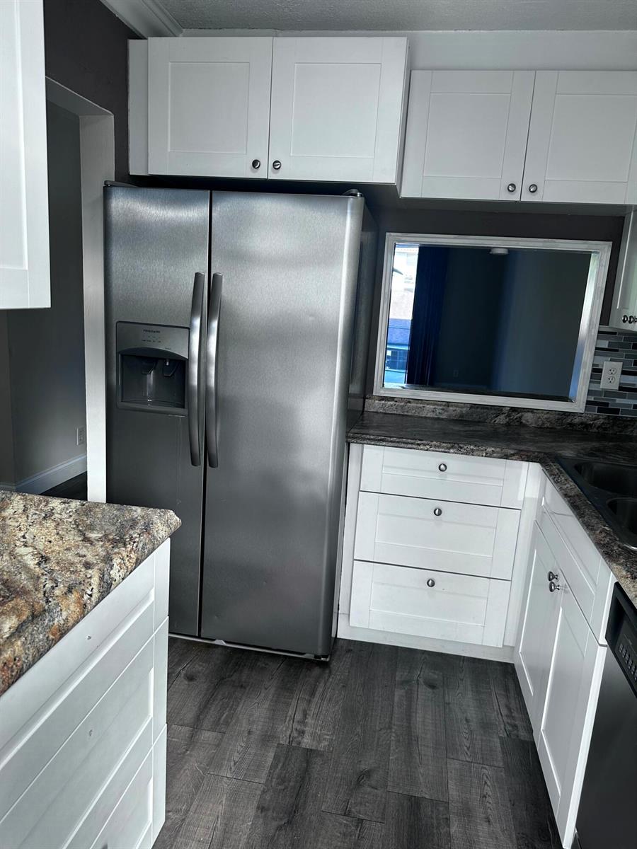 A kitchen features white cabinets, a stainless steel refrigerator, and dark granite countertops — 1040 SE 4th Avenue # 222, Deerfield Beach FL 33441, DEERFIELD BEACH, FL