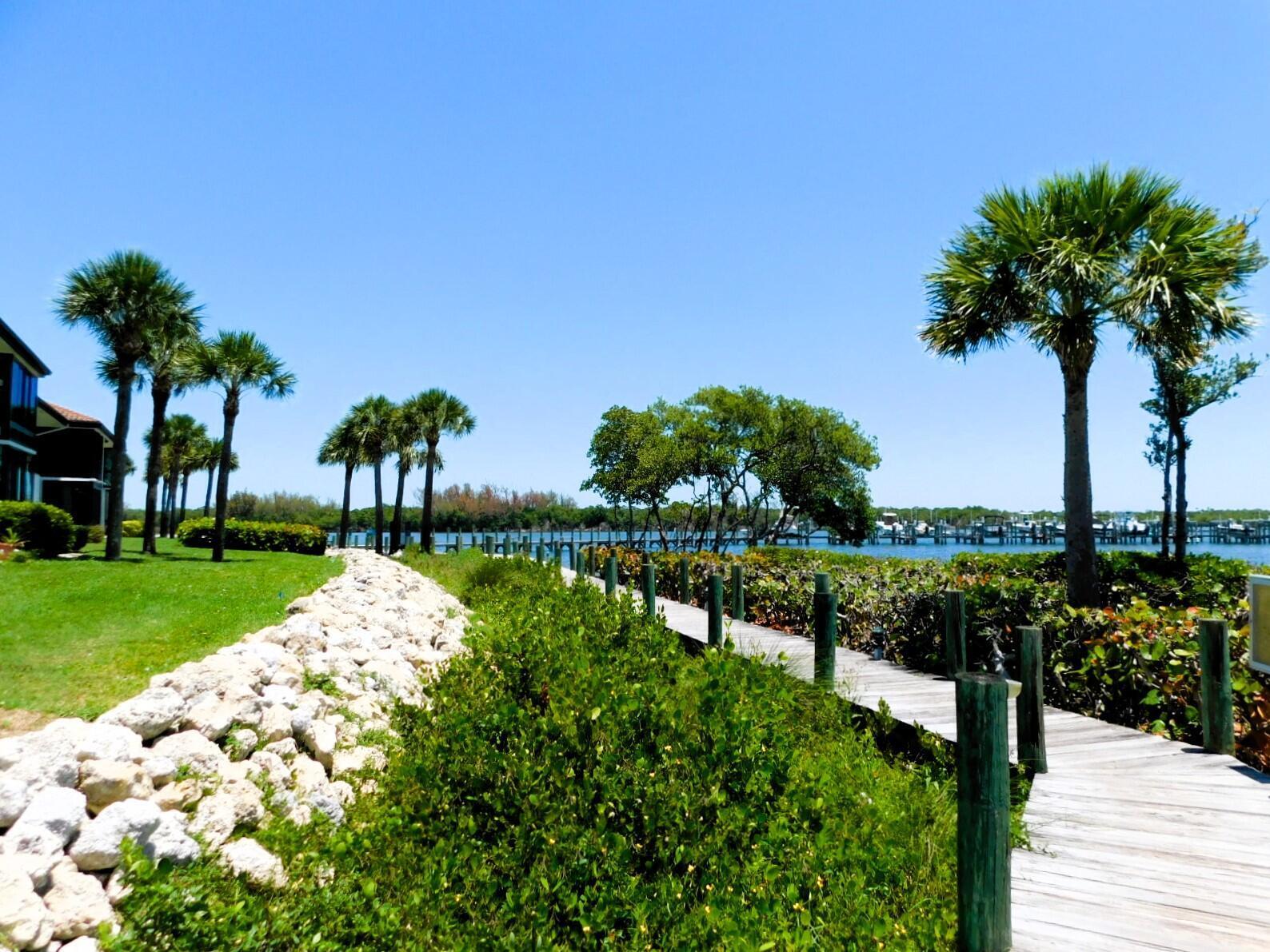 A wooden boardwalk leads past palm trees and a rocky shoreline toward a marina — 6062 SE Landing Way # 2, Stuart FL 34997, STUART, FL