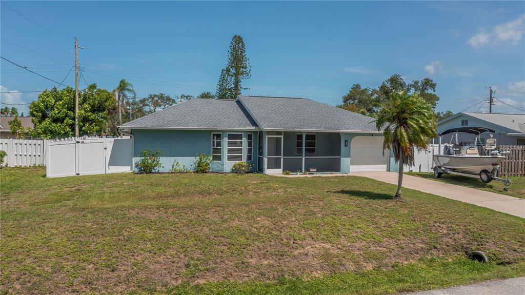 A single-story blue house with a gray roof, a front porch, and a boat parked nearby — 1510 NANTUCKET ROAD, VENICE, FL