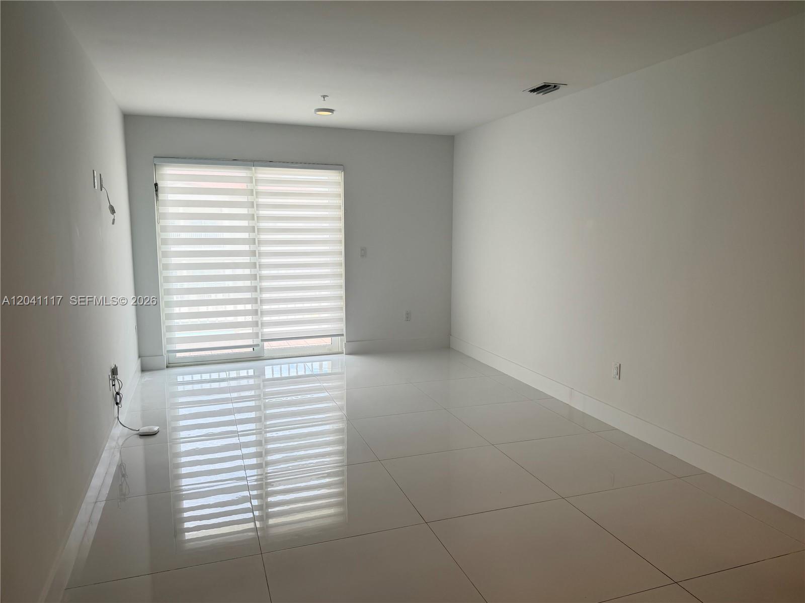 An empty room features white walls, large glossy floor tiles, and a sliding glass door — 10950 NW 82nd St # 416, Doral FL 33178, DORAL, FL