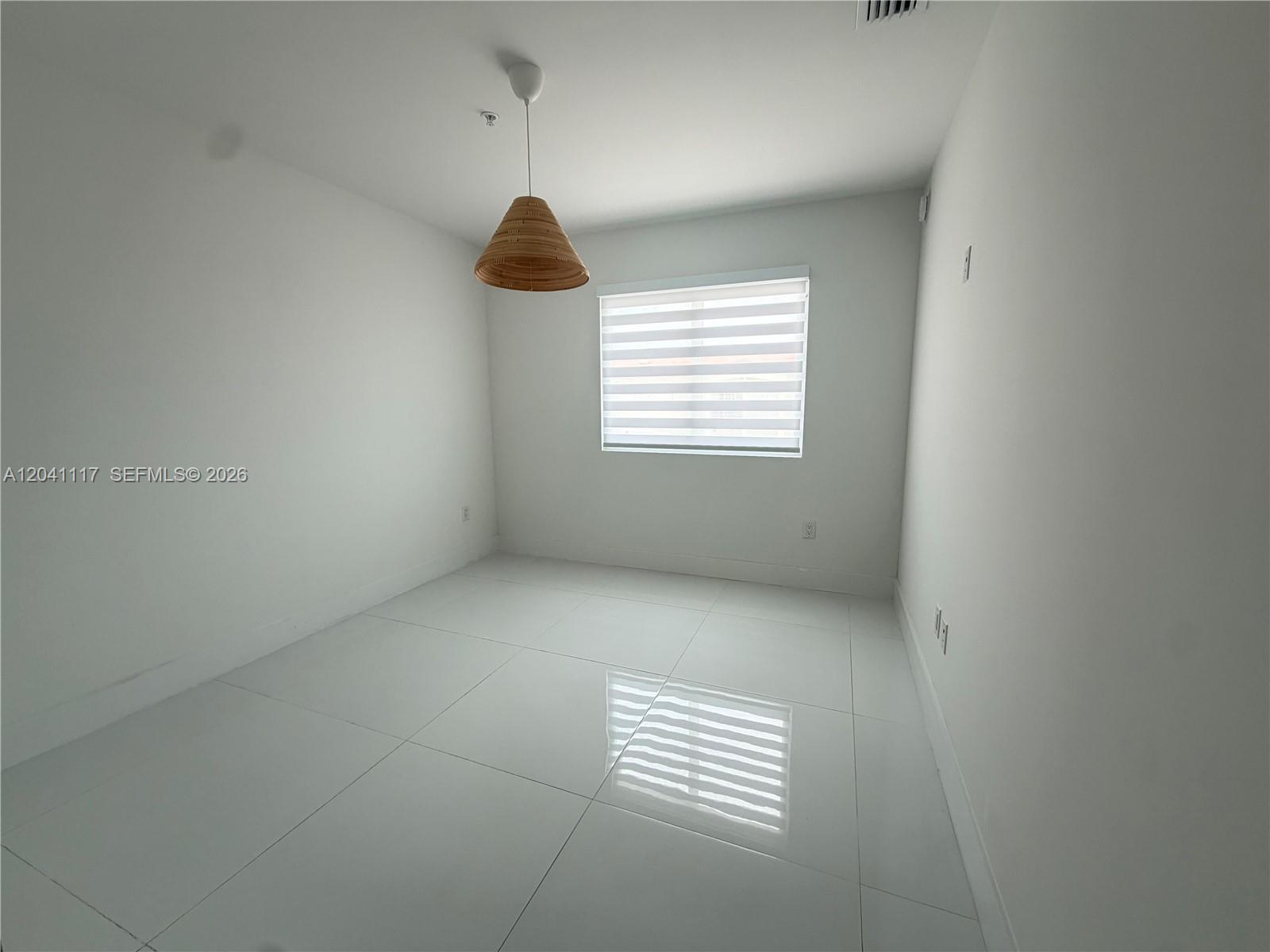 An empty room features white walls, large glossy floor tiles, and a hanging woven pendant light — 10950 NW 82nd St # 416, Doral FL 33178, DORAL, FL