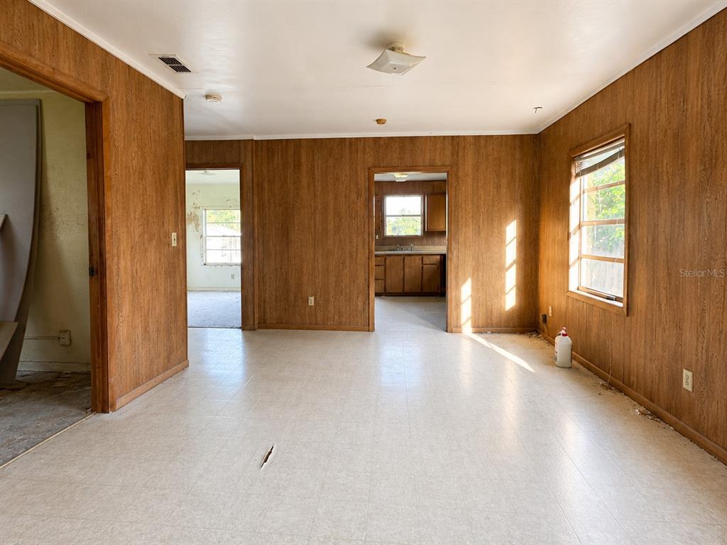 An interior view of a room with wood-paneled walls, light-colored flooring, and doorways leading elsewhere — 710 SEMINOLE STREET, WAUCHULA, FL