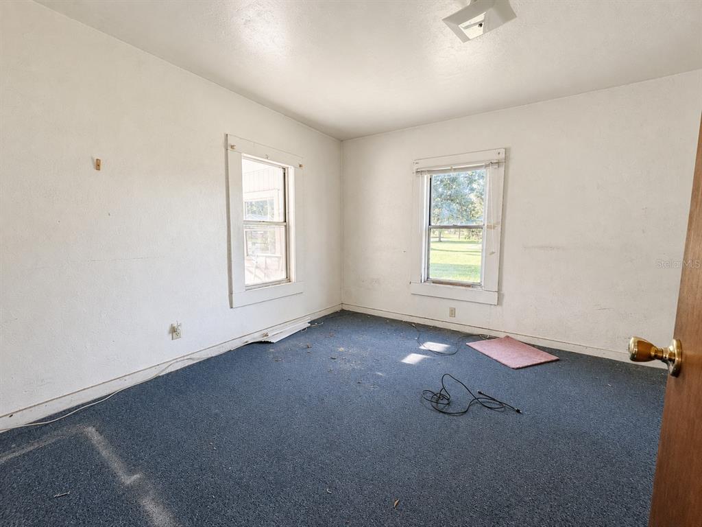 An empty bedroom features white walls, blue carpeting, and two windows with white trim — 710 SEMINOLE STREET, WAUCHULA, FL