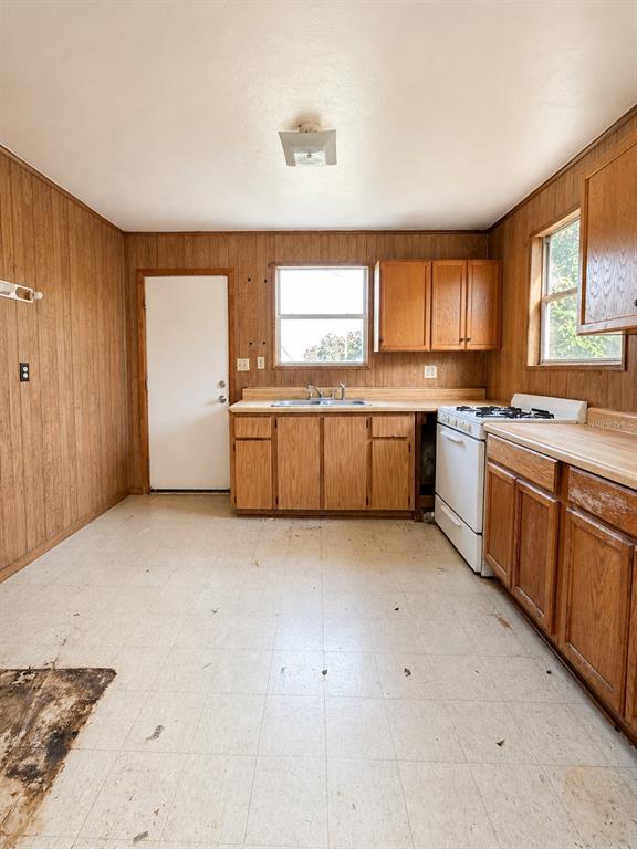 A kitchen features wood-paneled walls, wood cabinets, a white stove, and a light-colored tile floor — 710 SEMINOLE STREET, WAUCHULA, FL