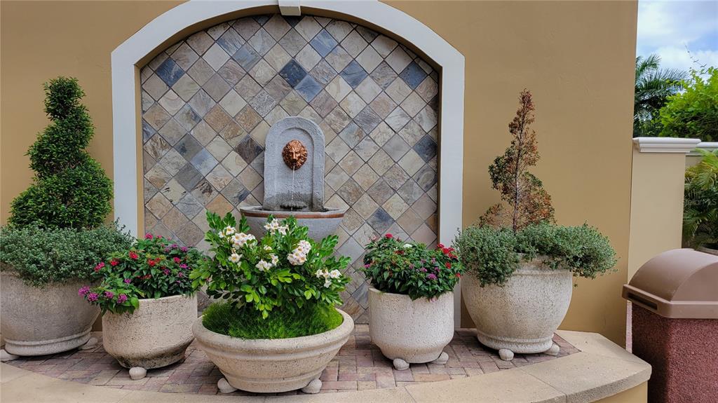 A stone wall fountain with a lion head spout sits behind four large potted plants — 1064 N TAMIAMI TRAIL UNIT 1325, SARASOTA, FL