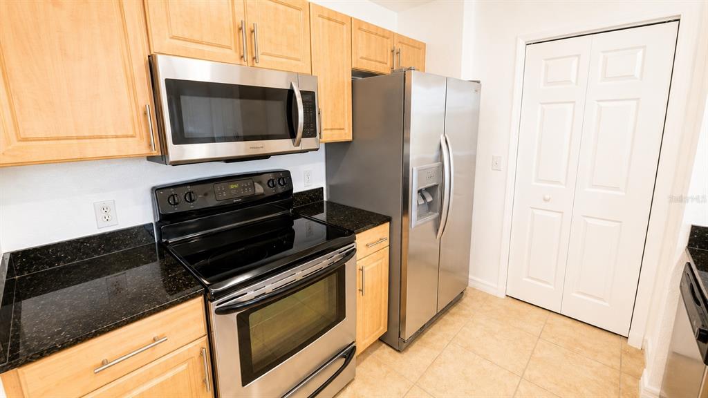 A kitchen features light wood cabinets, stainless steel appliances, and dark granite countertops — 1064 N TAMIAMI TRAIL UNIT 1325, SARASOTA, FL