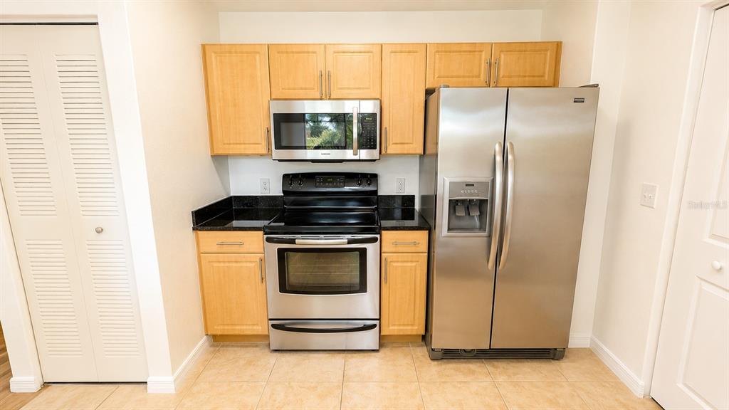 A kitchen features light wood cabinets, stainless steel appliances, and dark countertops — 1064 N TAMIAMI TRAIL UNIT 1325, SARASOTA, FL