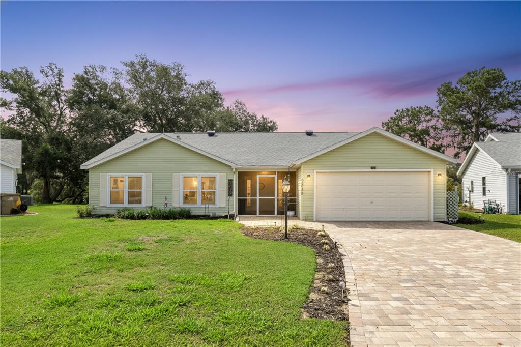A light green single-story house features a paved driveway, a garage, and a screened entryway — 5540 HAMLIN COURT, LEESBURG, FL