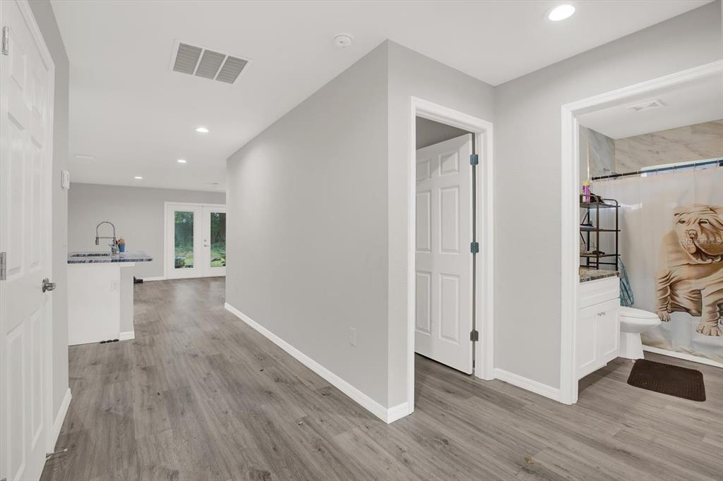 A hallway with gray wood-look flooring leads to a kitchen area, a bedroom, and a bathroom — 801 OSCEOLA AVENUE, WILDWOOD, FL