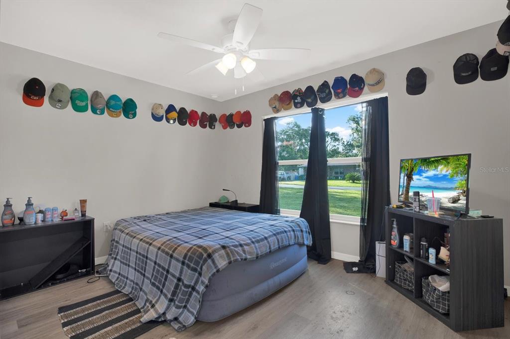 A bedroom features an air mattress, a television on a shelf, and hats displayed on walls — 801 OSCEOLA AVENUE, WILDWOOD, FL