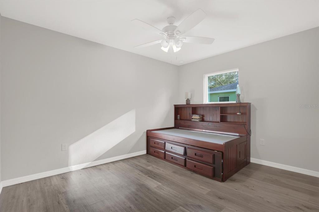 A bedroom with gray walls, wood-look flooring, a ceiling fan, and a wooden daybed — 801 OSCEOLA AVENUE, WILDWOOD, FL