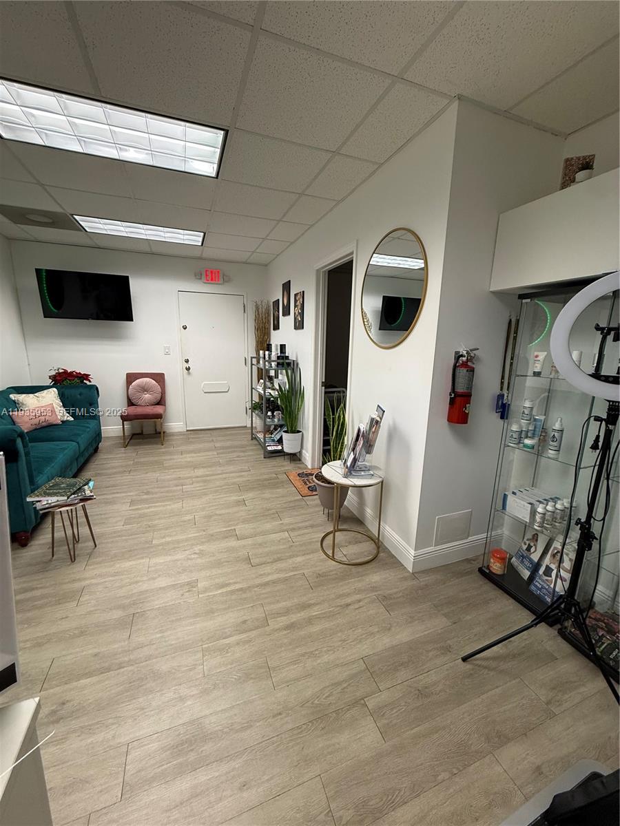 A waiting area features a teal sofa, wood-look flooring, a glass display case, and a mirror — 717 Ponce De Leon Blvd # 206, Coral Gables FL 33134, CORAL GABLES, FL