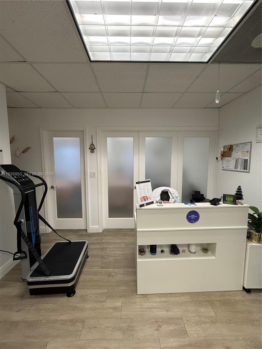 A reception area features a white desk, a vibration therapy machine, and frosted glass doors — 717 Ponce De Leon Blvd # 206, Coral Gables FL 33134, CORAL GABLES, FL