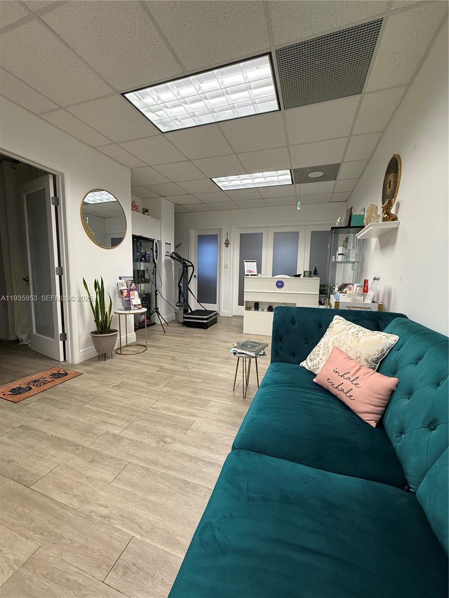 A waiting area features a teal tufted sofa, light wood flooring, and a reception desk — 717 Ponce De Leon Blvd # 206, Coral Gables FL 33134, CORAL GABLES, FL
