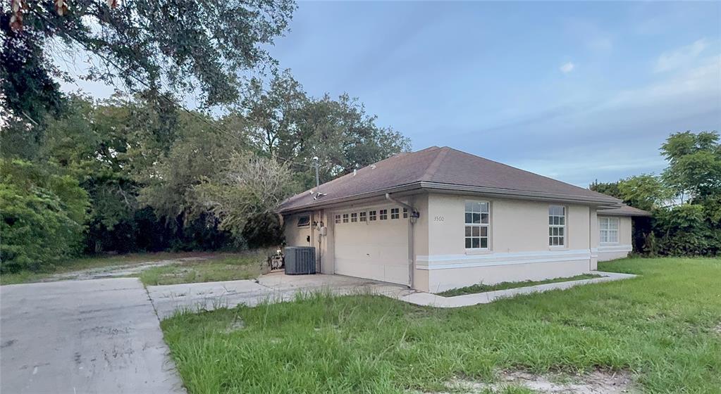 A beige, single-story house with a two-car garage and a hip roof sits on grass — 3500 W PRICE BOULEVARD, NORTH PORT, FL