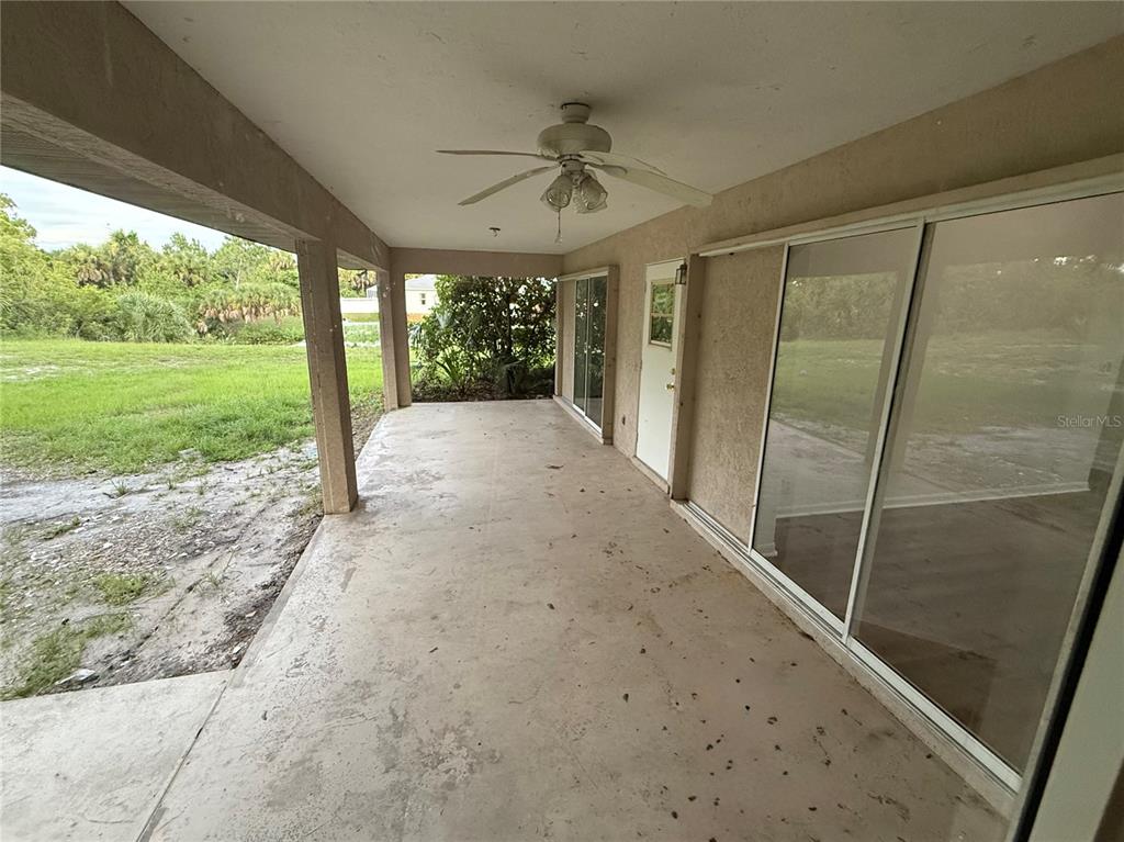 A covered concrete patio features a ceiling fan and sliding glass doors leading indoors — 3500 W PRICE BOULEVARD, NORTH PORT, FL