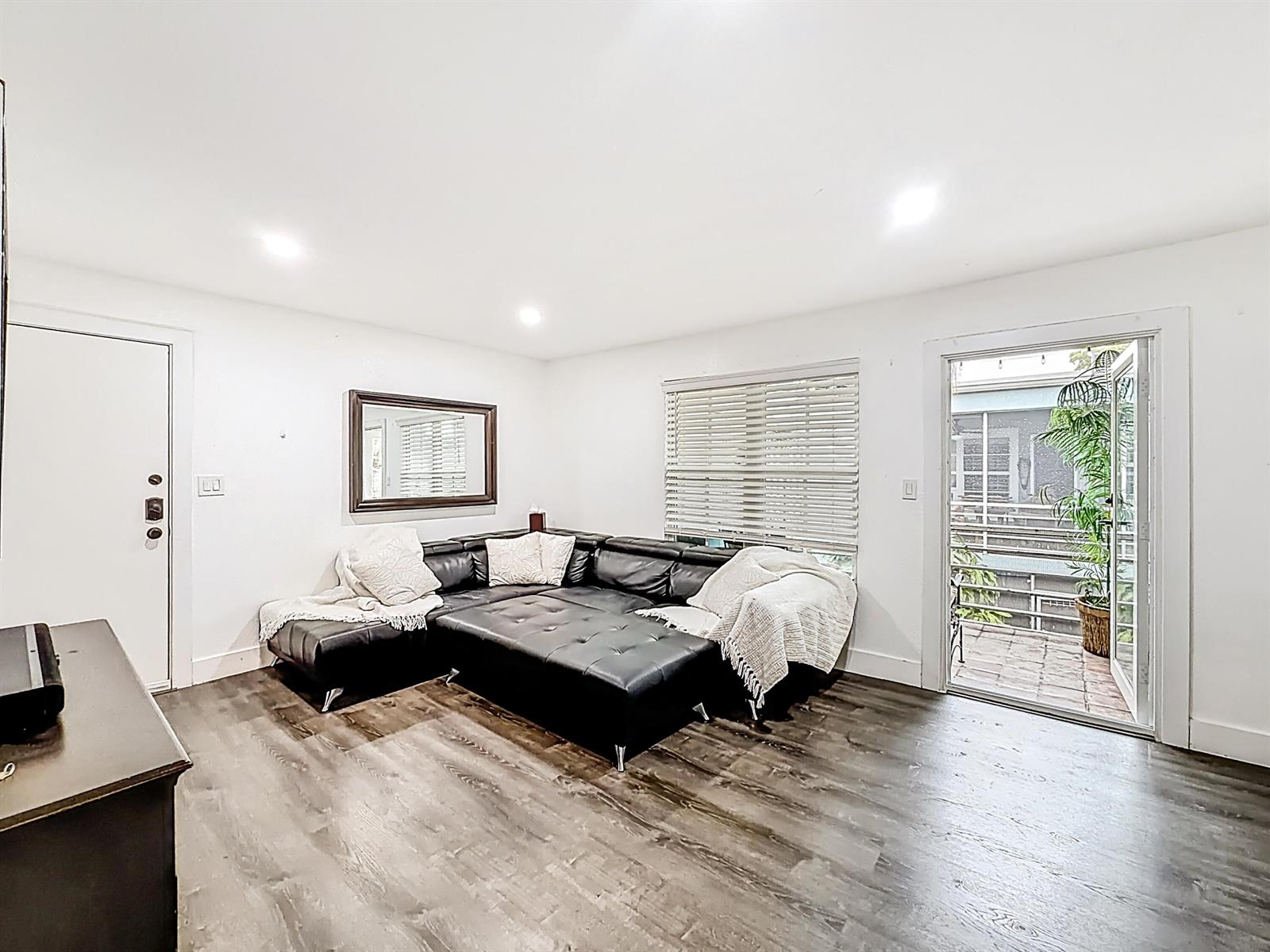 A living room features dark wood flooring, a black sectional sofa, and a glass door — 305 SE 11th Avenue, Pompano Beach FL 33060, POMPANO BEACH, FL