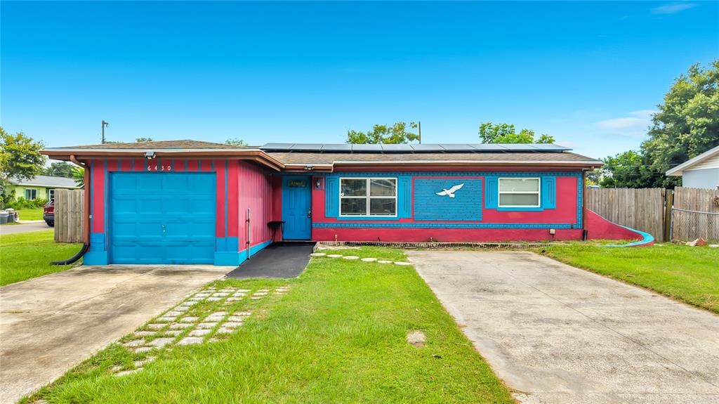 A single-story house with a bright pink and blue exterior, a garage, and solar panels — 6430 83RD AVENUE N, PINELLAS PARK, FL