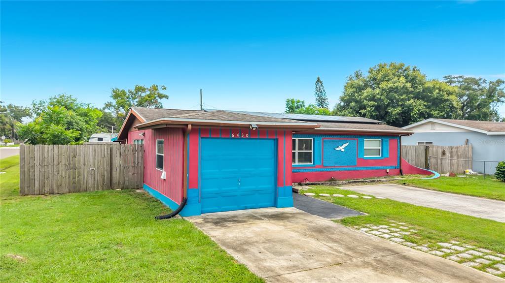 A single-story house with a blue garage door and bright pink and blue exterior walls — 6430 83RD AVENUE N, PINELLAS PARK, FL