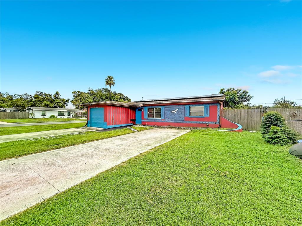 A single-story house with a red and blue exterior, a concrete driveway, and a lawn — 6430 83RD AVENUE N, PINELLAS PARK, FL