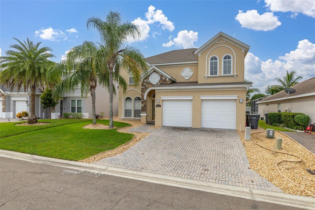 A two-story suburban house with a tan stucco exterior, stone accents, and a paved driveway — 2663 SAND HILL POINT CIRCLE, DAVENPORT, FL