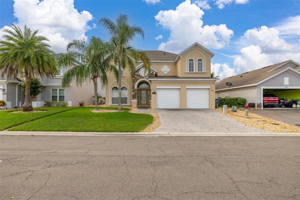 A two-story suburban house with a tan stucco exterior, stone accents, and a two-car garage — 2663 SAND HILL POINT CIRCLE, DAVENPORT, FL