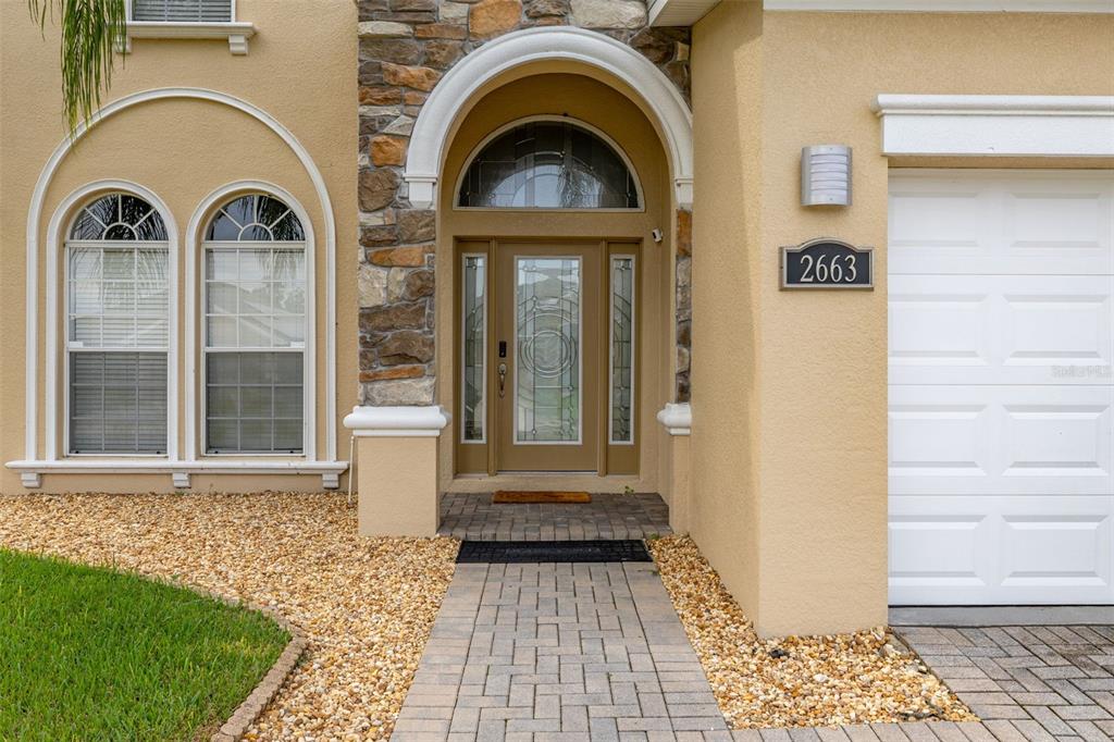 The exterior of a house features a stone-accented entryway, a glass-paneled door, and a garage — 2663 SAND HILL POINT CIRCLE, DAVENPORT, FL