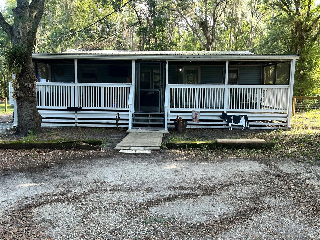 A single-story house with a large front porch and white railing sits in a wooded area — 5237 TURTLE DOVE TRAIL, LAKELAND, FL