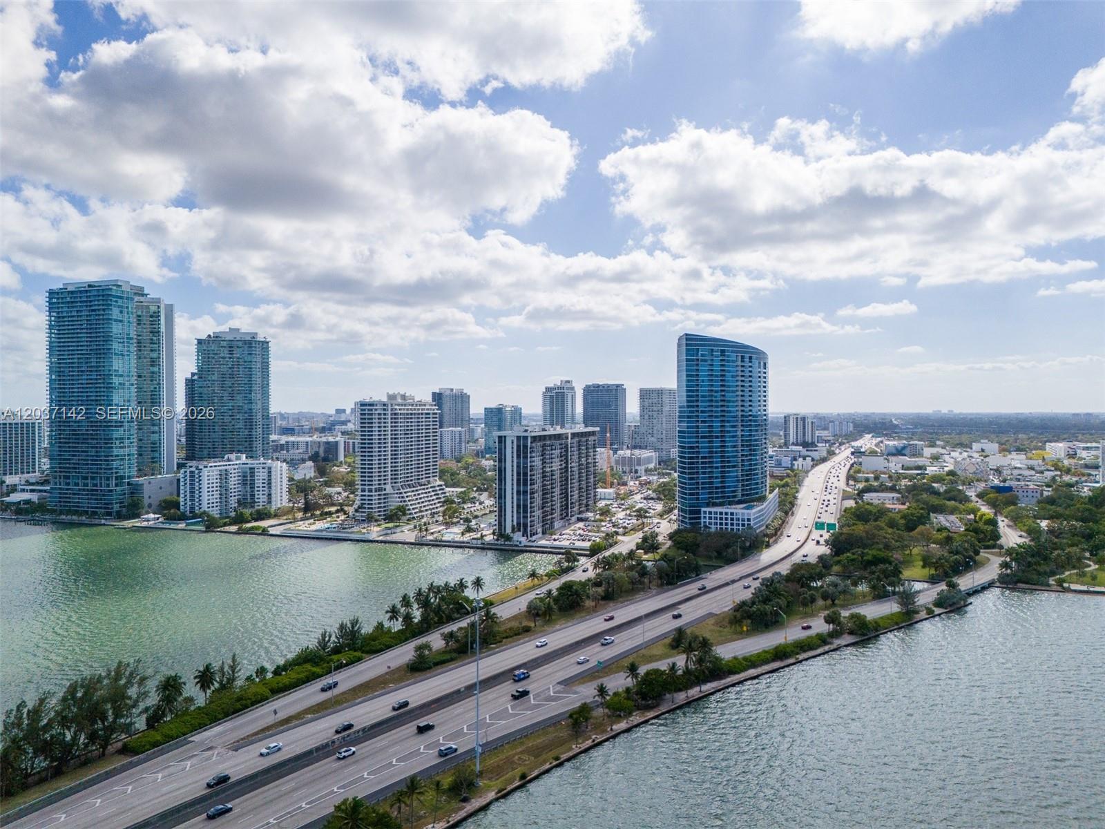An aerial view shows a highway bridge crossing water toward a city skyline with skyscrapers — 600 NE 36th St # 1006, Miami FL 33137, MIAMI, FL